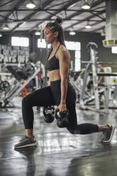 Female athlete doing lunges with kettlebells - VEGF01472