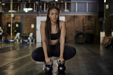 Confident female athlete with arms akimbo standing in gym stock photo