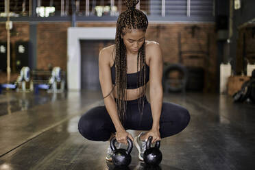 Weibliche Athletin trainiert mit Kettlebells im Fitnessstudio - VEGF01477