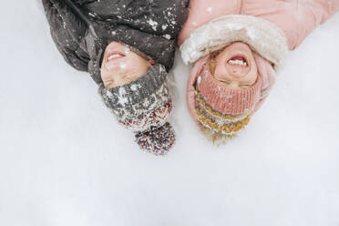 Portrait of two siblings lying on snow - EYAF00852