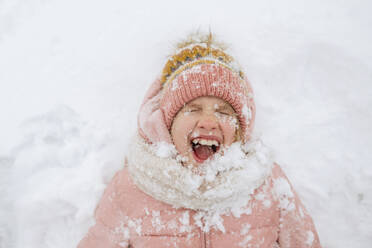 Portrait of screaming girl lying on snow - EYAF00853