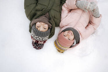 Porträt von zwei lächelnden Geschwistern im Schnee liegend - EYAF00855