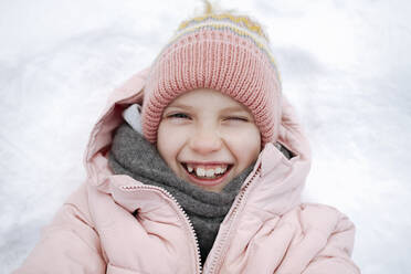 Portrait of happy girl lying on snow - EYAF00857