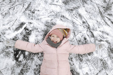 Portrait of happy girl with arms outstretched lying on ice - EYAF00861