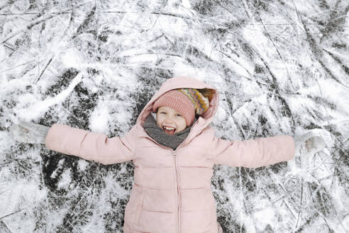 Porträt eines glücklichen Mädchens mit ausgestreckten Armen auf Eis liegend - EYAF00861