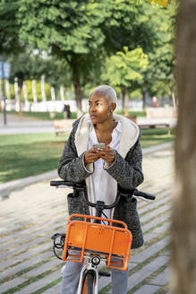 Geschäftsfrau, die in der Stadt mit dem Fahrrad pendelt und ihr Smartphone benutzt - AFVF05066