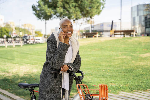 Geschäftsfrau, die in der Stadt mit dem Fahrrad pendelt und ihr Smartphone benutzt - AFVF05068