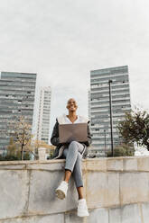 Casual businesswoman sitting in the city, using laptop - AFVF05070