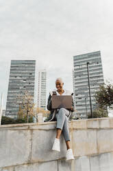 Casual businesswoman sitting in the city, using laptop - AFVF05071