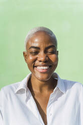 Porträt einer lachenden Frau vor einer grünen Wand - AFVF05082