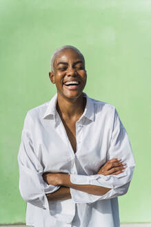 Portrait of laughing woman in front of green wall - AFVF05083