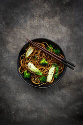 Overhead view of bowl of soba noodles with pak choi and broccoli, soy sauce and black sesame - LVF08546