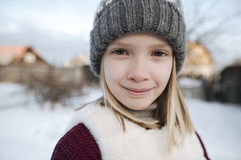 Porträt eines lächelnden Mädchens mit Wollmütze im Winter, lizenzfreies Stockfoto