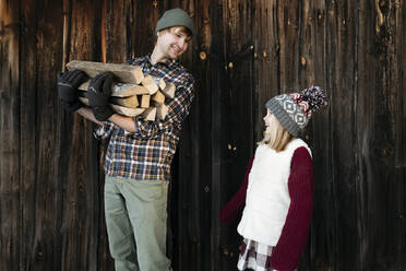 Glücklicher Vater und Tochter halten Brennholz im Winter - EYAF00886