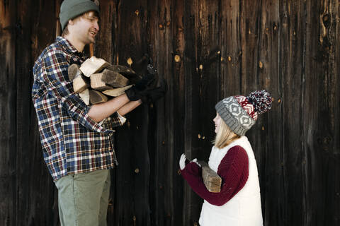 Glücklicher Vater und Tochter halten Brennholz im Winter, lizenzfreies Stockfoto