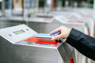 Nahaufnahme einer Frau, die in der U-Bahn mit ihrem Smartphone bezahlt - KIJF02889