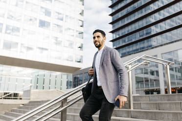 Casual young businessman walking down stairs in the city - JRFF03982