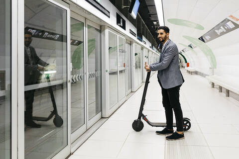 Junger Geschäftsmann mit Elektroroller in der U-Bahn-Station, lizenzfreies Stockfoto