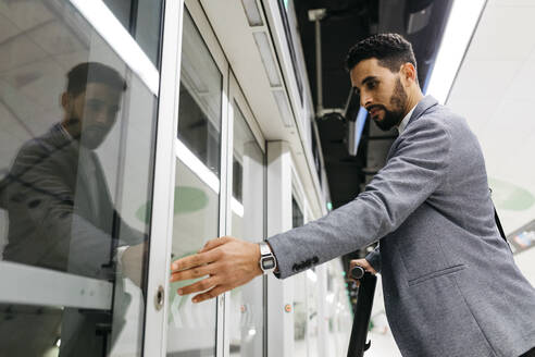 Junger Geschäftsmann drückt den Öffnungsknopf, um in einen automatischen U-Bahn-Zug einzusteigen - JRFF04000