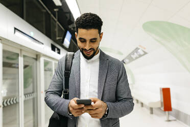 Young businessman using cell phone in subway station - JRFF04002