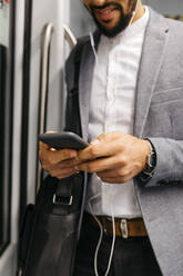 Close-up of businessman using cell phone on the subway - JRFF04014