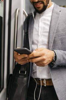 Nahaufnahme eines Geschäftsmannes, der in der U-Bahn ein Handy benutzt - JRFF04014