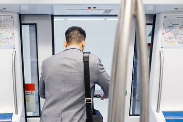 Rückansicht eines jungen Geschäftsmannes mit Elektroroller beim Verlassen der U-Bahn - JRFF04016