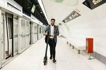 Junger Geschäftsmann mit Elektroroller in der U-Bahn-Station - JRFF04017