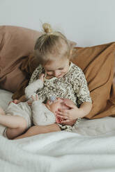 Girl with newborn sibling on bed - JOHF05585
