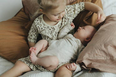 Mädchen mit neugeborenem Geschwisterchen auf dem Bett - JOHF05589