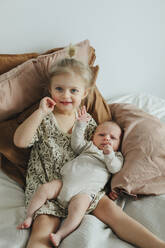Mädchen mit neugeborenem Geschwisterchen auf dem Bett - JOHF05591