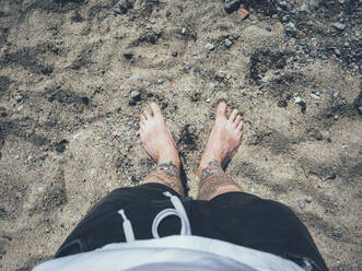 Man standing on sandy beach, low section - JOHF05648