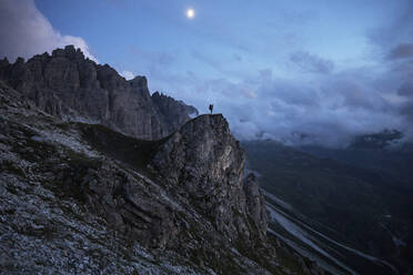 Wanderer, der in der Dämmerung auf einem Felsvorsprung steht und auf die Berge blickt - CVF01534