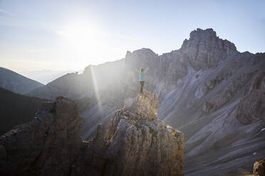 Hiker standing on rock spur, looking at the mountains - CVF01543