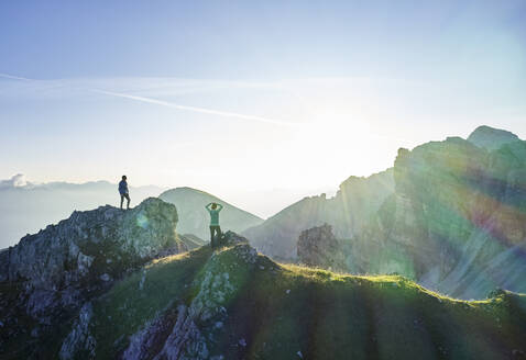 Hikers standing on rock spur, looking at the mountains - CVF01553