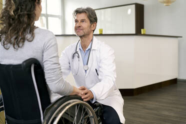 Arzt kümmert sich um eine Patientin im Rollstuhl - PHDF00032