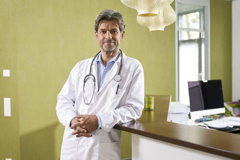 Porträt eines selbstbewussten Arztes am Empfang seiner Arztpraxis - PHDF00033