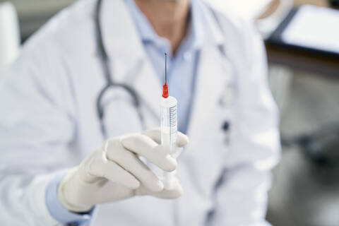 Doctor holding syringe in his medical practice stock photo