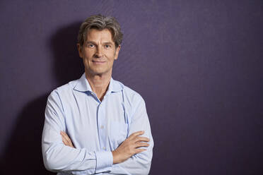 Portrait of confident businessman in front of a purple wall - PHDF00071