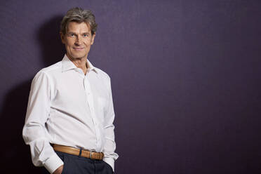 Portrait of confident businessman in front of a purple wall - PHDF00072