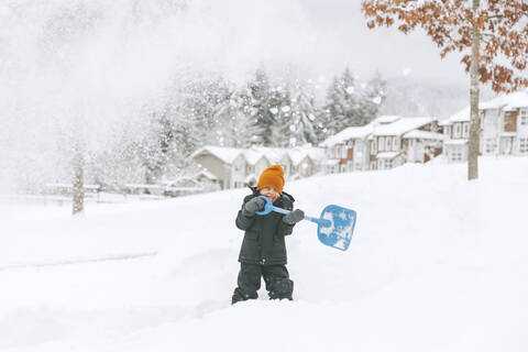 Lachender kleiner Junge beim Schneeschaufeln, Vancouver, Kanada, lizenzfreies Stockfoto