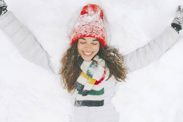 Portrait of happy woman lying on snow - CMSF00077