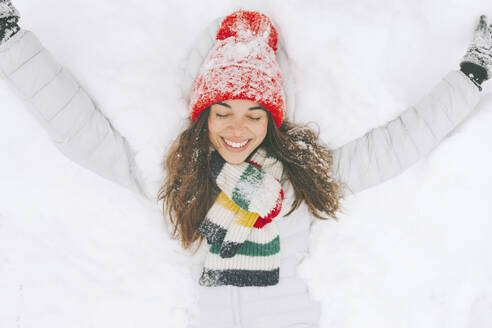 Porträt einer glücklichen Frau, die im Schnee liegt - CMSF00077