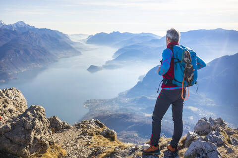 Hiker standing on mountain, looking at Lake Como, Italy stock photo