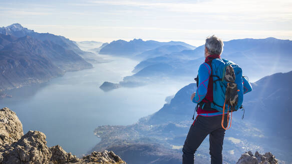 Wanderer auf einem Berg stehend, Blick auf den Comer See, Italien - MCVF00193