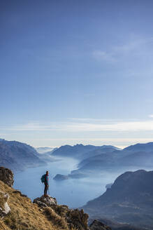 Wanderer auf einem Berg stehend, Blick auf den Comer See, Italien - MCVF00196