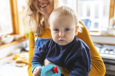 Porträt eines kleinen Jungen, der von seiner Mutter gehalten wird und ein lustiges Gesicht macht - WPEF02458