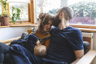 Woman on the sofa breastfeeding her little son and sharing time with her husband - WPEF02477