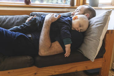 Vater und Sohn schlafen zusammen auf dem Sofa - WPEF02483