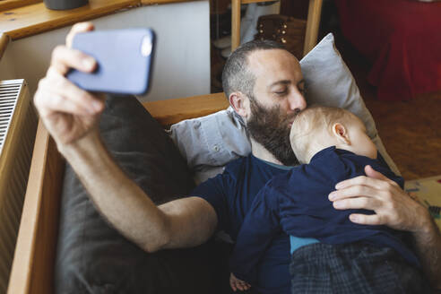 Mann macht ein Selfie mit seinem süßen schlafenden Sohn auf dem Sofa - WPEF02486